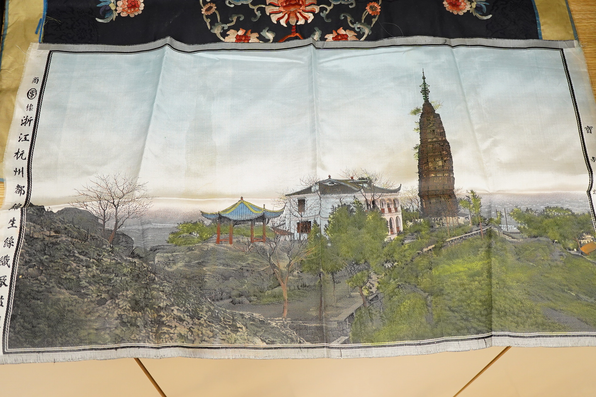An early 20th century Chinese blue silk and coloured floral embroidered table cover, with a later Chinese printed panel of a house, pagoda and monument along a river bank, embroidery 78cm x 62cm. Condition - the edging t